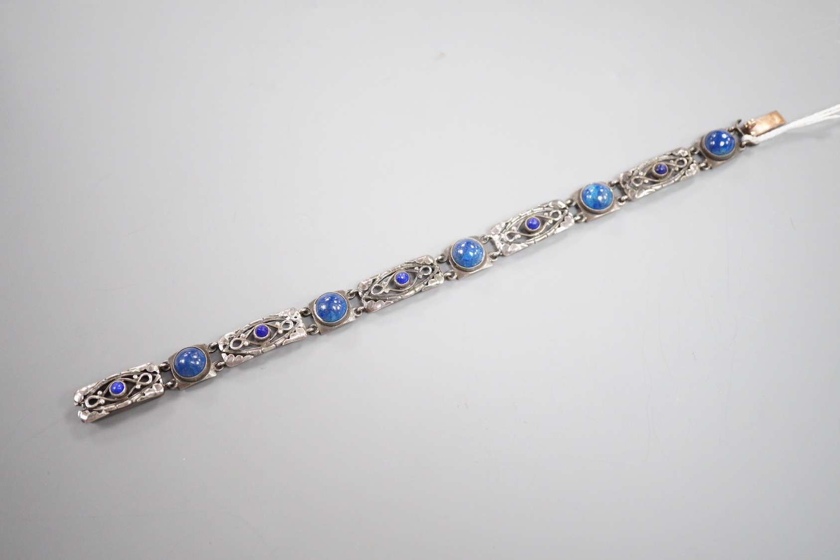 A stylish early 20th century white metal and two colour ten stone lapis lazuli?? or possibly enamel?? cabochon set bracelet, stamped 'Liberty Sterling', 18.3cm.